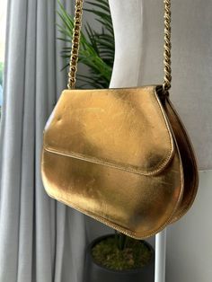 Bronze leather shoulder bag with gold chain strap. Bag is fully lined with one inner zippered pocket, and a snap closure in the front. The strap does have some weight to it. In overall used condition with some wear to the front, including some scratches and signs of wear. No label or tags. Measurements Across 11in/28cm Height 7.25in/18.5cm *Please keep in mind that unless otherwise noted, all items in my shop are used or previously owned, normal wear and tear is expected, flaws that are noted ar Vintage Gold Shoulder Bag With Gold-tone Hardware, Classic Gold Shoulder Bag For Evening, Leather Shoulder Bag With Gold Chain For Evening, Evening Leather Shoulder Bag With Gold Chain, Gold Satchel Shoulder Bag For Formal Events, Gold Satchel Shoulder Bag For Formal Occasions, Gold Bag With Gold Clasp For Everyday Use, Vintage Gold Shoulder Bag For Formal Occasions, Gold Bags With Gold Clasp For Everyday Use