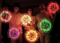 four people are holding lighted firework in the dark with their arms around each other