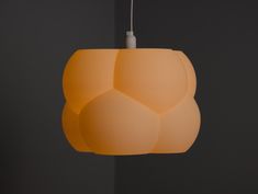 an orange light hanging from a ceiling in a room with black walls and flooring