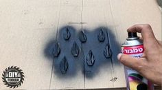 a hand holding a spray bottle next to some fake black shoes on the ground with holes in it