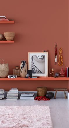 a shelf with books and other items on it in front of a wall painted pink