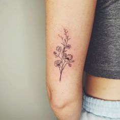 a woman's arm with a small flower tattoo on the left side of her arm