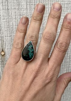 A lovely natural large teardrop Tibetan Turquoise has been set in sterling silver with a handmade ring band. This stone is lovely with an opaque black background and stunning bright turquoise blue veining. The ring band has been hand hammered as an accenting detail. The stone is 28mm x 18mm in size with a height of 6mm. Size 6.5, cannot be sized up or down. Turquoise is the birthstone for December! Bohemian Sterling Silver Turquoise Teardrop Ring, Unique Teardrop Ring With Natural Stones, Sterling Silver Teardrop Rings With Natural Stones, Teardrop Turquoise Sterling Silver Rings, Sterling Silver Teardrop Rings, Turquoise Teardrop Gemstone Rings, Unique Turquoise Teardrop Rings, Unique Teardrop Turquoise Rings, Unique Sterling Silver Teardrop Turquoise Ring