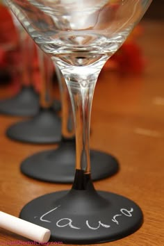 three wine glasses sitting on top of black coasters with writing on the bottom one