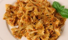 a white plate topped with pasta and meat covered in sauce, garnished with green leaves