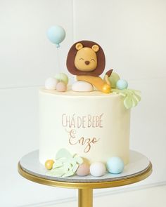 a white cake with a lion on top and balloons in the shape of animals sitting on it