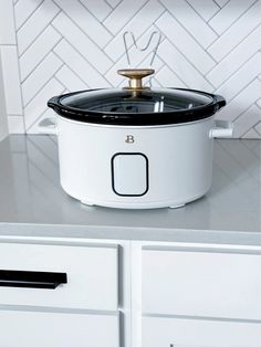 a white crock pot sitting on top of a counter next to drawers and cabinets