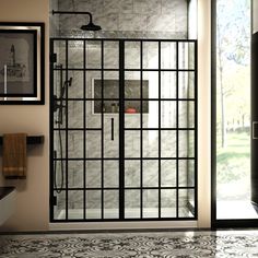 a bathroom with a glass shower door and tiled flooring, framed pictures on the wall