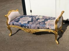 an ornately decorated bench sitting on the ground in front of a white cabinet and door