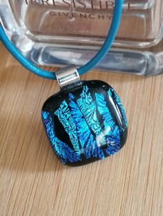 a glass pendant is sitting on a wooden table next to a blue cord and bottle