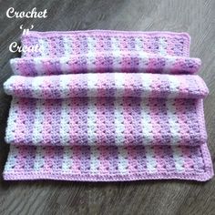 a pink and white crocheted blanket sitting on top of a wooden floor