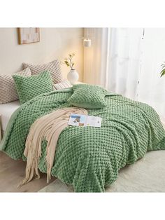 a bed with green comforter and pillows on it