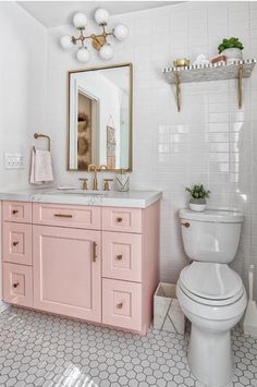 a white toilet sitting next to a pink sink in a bathroom under a large mirror