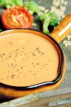 a bowl filled with soup next to broccoli and tomatoes