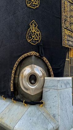 an elaborately decorated black and gold kabab sits in front of a stone pillar