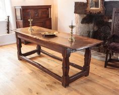 a wooden table with two candles on it in front of a fire place and fireplace