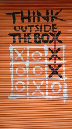 an orange garage door with graffiti on it and the words think outside the box written in black