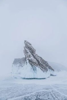 an iceberg in the middle of nowhere with snow on it's sides and mountains