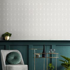 a chair and table in front of a wallpapered room with green walls, plants and vases