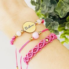 three bracelets with personalized charms on the wrist and one is pink, white and gold