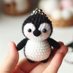 a small black and white penguin keychain in someone's hand