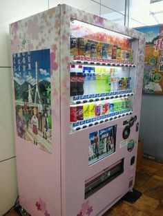 a pink vending machine sitting on top of a wooden floor next to a wall