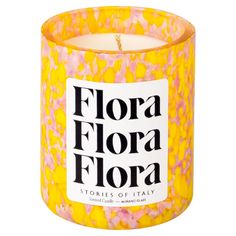 a candle that is yellow and pink with the words flora flora written in black on it