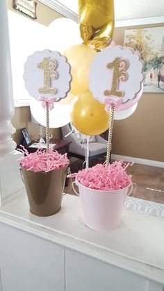 two buckets filled with pink and yellow flowers sitting on top of a white table