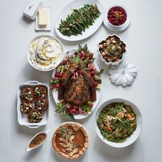 a white table topped with plates and bowls filled with different types of food next to each other