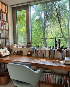 a chair sitting in front of a window filled with lots of books next to a book shelf