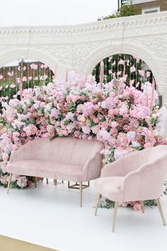 pink chairs and flowers on display in front of a fence