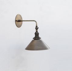 an old - fashioned wall light is mounted on the wall with a metal arm and shade