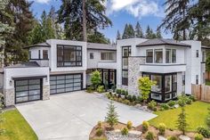 a large white house with lots of windows and trees in the front yard, on a sunny day