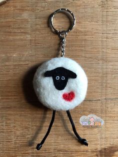 a sheep keychain is hanging on a wooden surface