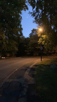 an empty street at night with no cars or people on the road and trees in the background