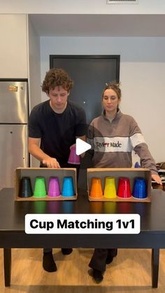 two people standing in front of a table with cups on it and the words cup matching 1v1