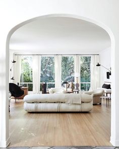 a living room filled with white furniture and lots of window sill space next to a fireplace