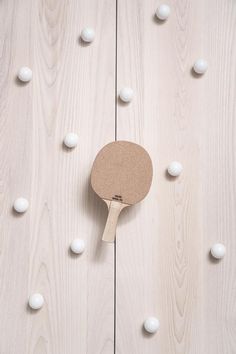 a ping pong paddle sitting on top of a wooden table next to white balls