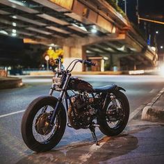 a motorcycle is parked on the side of the road near an overpass at night