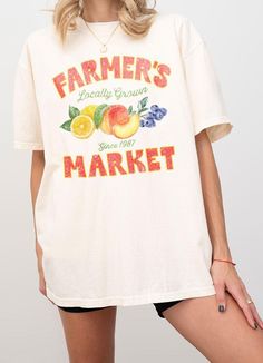 This Farmer's Market T-Shirt offers a relaxed adult fit and is made with heavyweight Comfort Colors for ultimate comfort. The trendy vintage retro design features a typography of "Farmer's Market - Locally Grown" with a colorful illustration of peach, lemon, and berry. Show your support for local produce while looking stylish and feeling comfortable. S:M:L:XL *Size Chart Available Garment Dyed Cotton 100% Machine Wash Delicate cycle with like colors Retro Faded T-shirt With Letter Print, Vintage Text Print T-shirt For Spring, Vintage Short Sleeve T-shirt With Lettering, Faded Retro T-shirt For Summer, Faded Crew Neck T-shirt With Letter Print, Oversized Faded Graphic Tee, Vintage Oversized Tops With Lettering, Vintage Oversized Top With Lettering, Oversized Acid Wash Vintage T-shirt