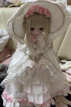 a doll is wearing a white dress and hat