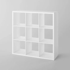 a white bookcase with several compartments on the top and bottom, against a gray background