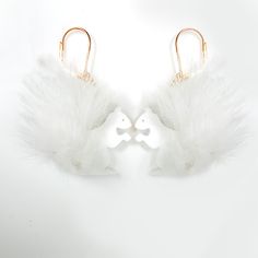 two white angel wings are attached to gold hoop earrings on a white background with an earring in the middle