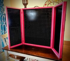 an open pink and black board with polka dots on the sides sitting on a wooden table