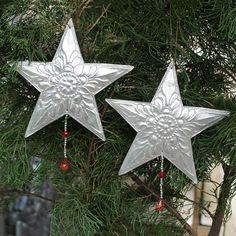 two silver metal stars hanging from a tree