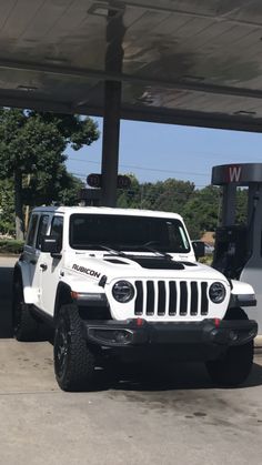 a white jeep parked in front of a gas station