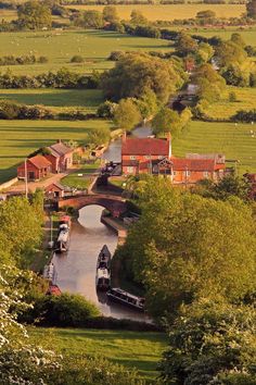 a river running through a lush green countryside next to houses and trees in the distance