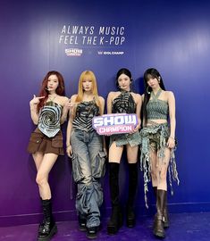 four women standing next to each other in front of a purple wall