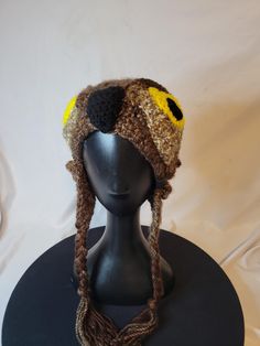 a black mannequin head wearing a knitted hat with yellow eyes on it