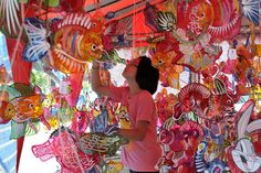 a woman standing in front of a display of colorful kites hanging from the ceiling